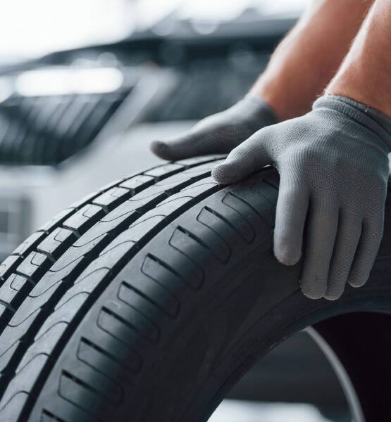 Hands only. Mechanic holding a tire at the repair garage. Replacement of winter and summer tires.